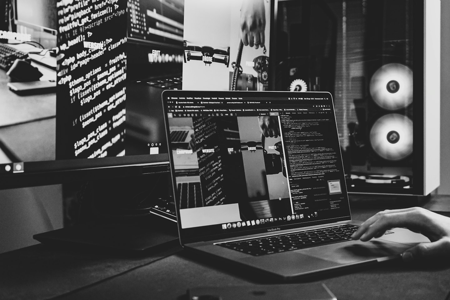 Hand using a MacBook Pro trackpad with coding on screen.