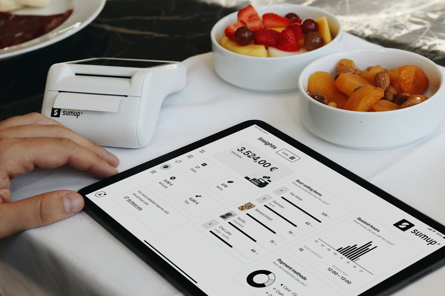 Person's hand touches tablet showing SumUp business dashboard.